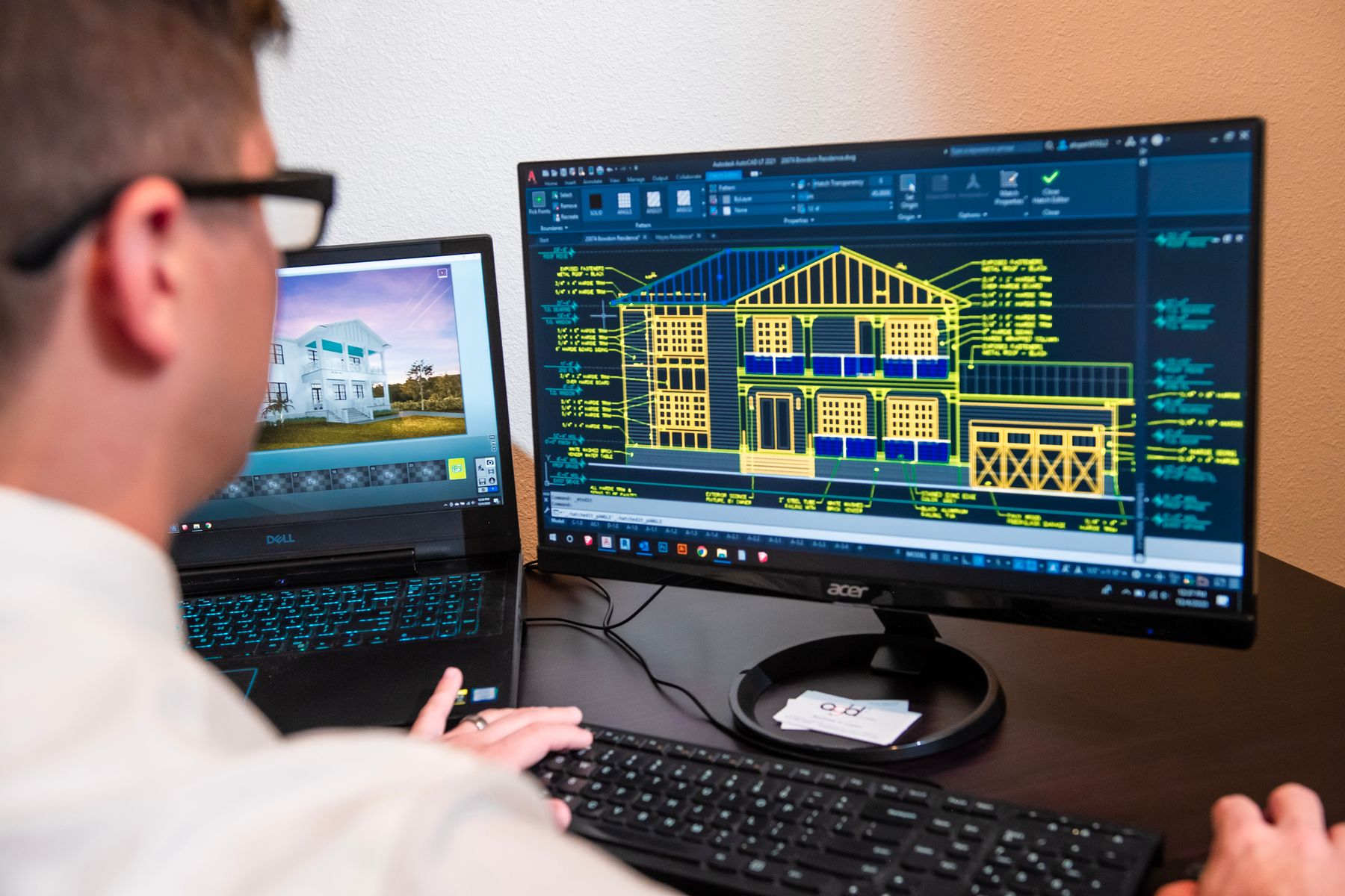 Engineer working with architectural drawings across two displays